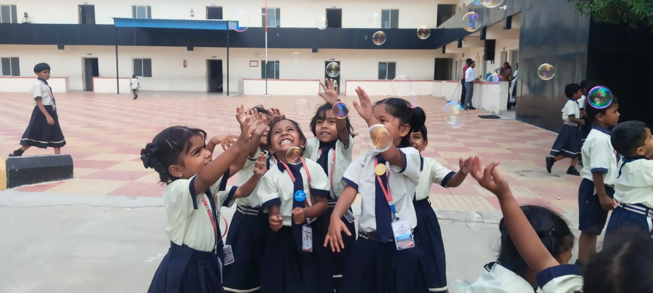 Young John's Academy students playing with bubbles in the courtyard